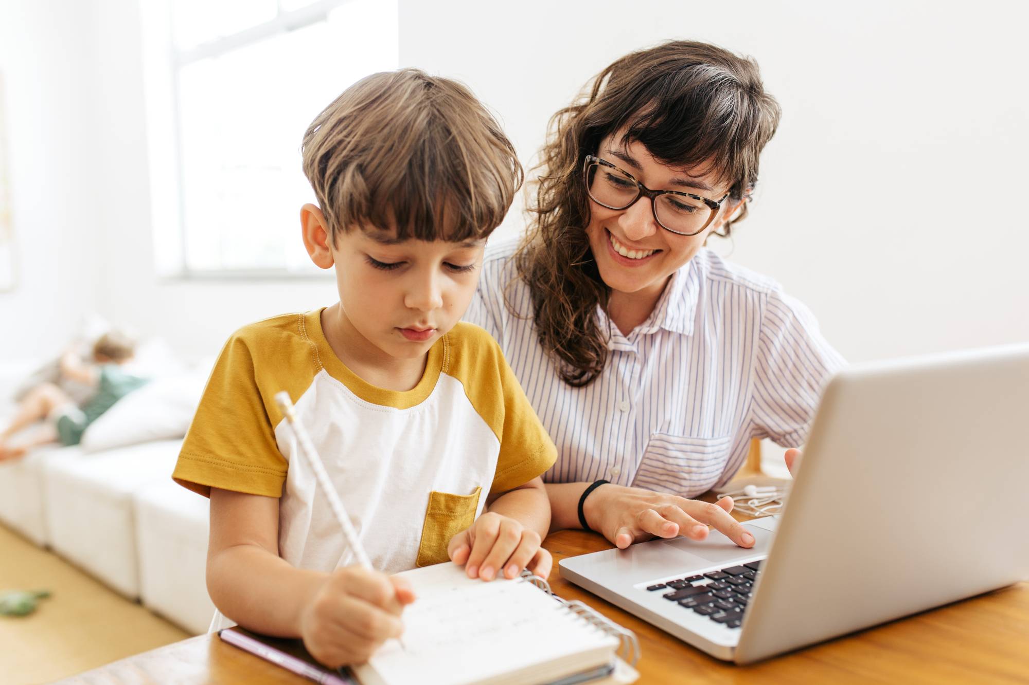 En pojke och en kvinna sitter vid ett bord och en dator och pluggar tillsammans.